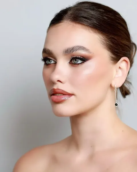 Primer plano de una mujer de perfil con los ojos maquillados en tonos ahumados y los labios nude