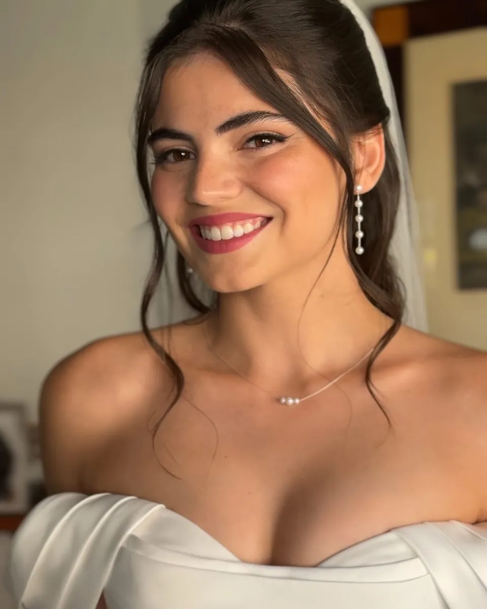 Novia con velo y el pelo recogido, sonriendo con un vestido blanco de corsé